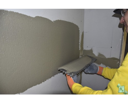 Un artisan applique de l''enduit sur un mur à l''aide d''une taloche.
