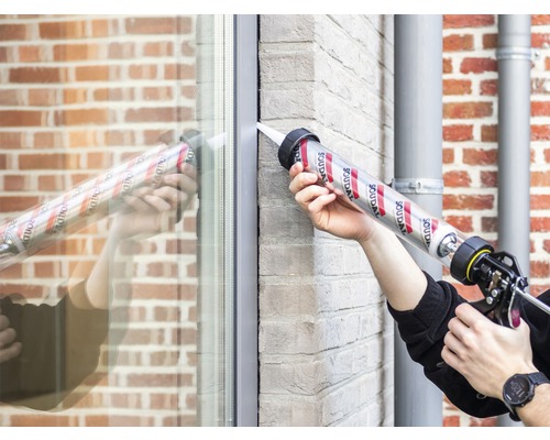 Personne scelle une fenêtre avec du mastic et un pistolet à cartouche