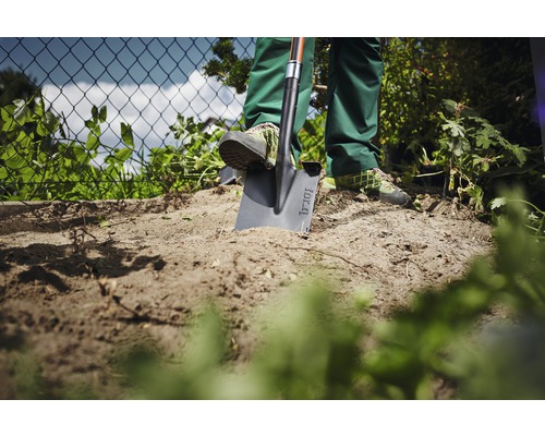 Gartenszene mit Person, die einen Spaten in die Erde sticht