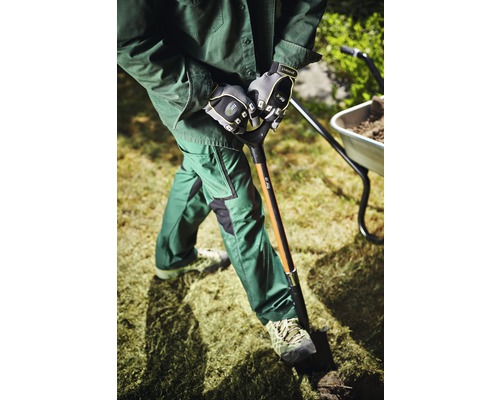 Person mit Handschuhen, Schaufel und Schubkarre bei der Gartenarbeit