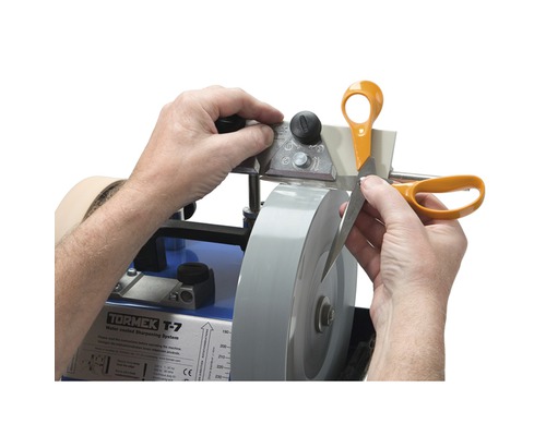 Personne aiguisant des ciseaux avec une affûteuse Tormek T-7