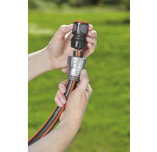 Deux mains raccordent un tuyau d''arrosage à un raccord.