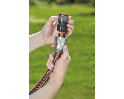 Deux mains raccordent un tuyau d''arrosage à un raccord.