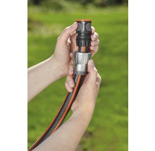 Deux mains raccordent un tuyau d''arrosage à un raccord de tuyau.