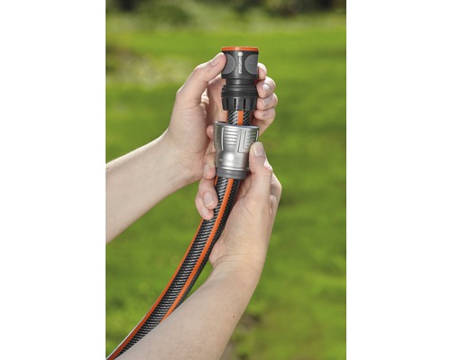 Deux mains raccordent un tuyau d''arrosage à un raccord de tuyau.