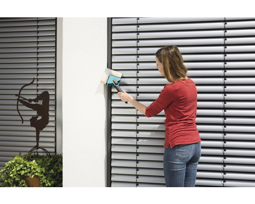 Frau reinigt Jalousien mit einer Bürste.