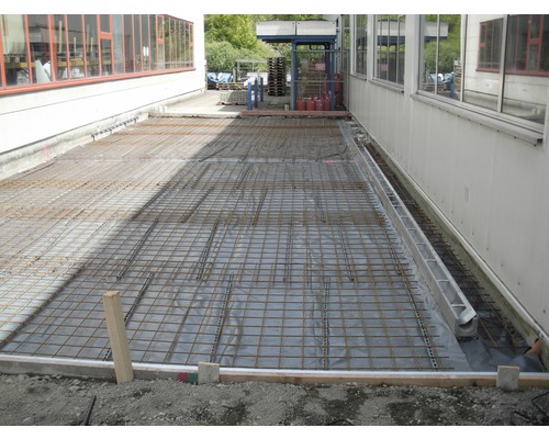 Préparation de chantier avec treillis d''armature et film de construction pour travaux de bétonnage à l''extérieur.