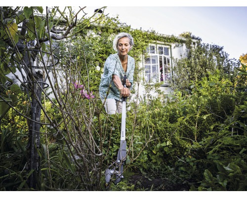 Frau benutzt eine Unkrautwurzelzange im Garten.