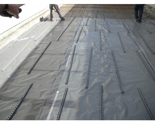 Travaux de construction avec film de protection et entretoises sur un chantier.