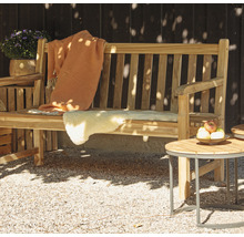 Scène de jardin avec un banc en bois, une couverture en laine, une peau de mouton et une table d''appoint avec une coupe de fruits