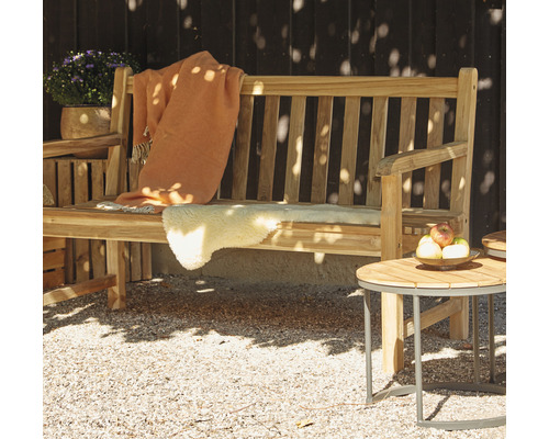 Scène de jardin avec un banc en bois, une couverture en laine, une peau de mouton et une table d''appoint avec une coupe de fruits