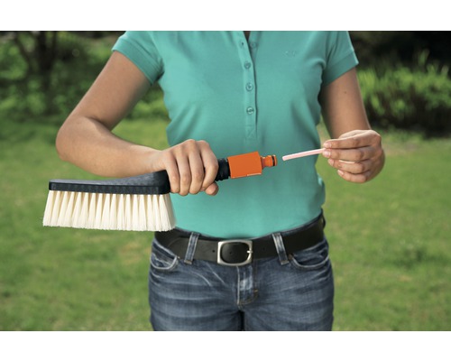 Person verbindet Bürste mit Wasseranschluss und Reinigungsstab