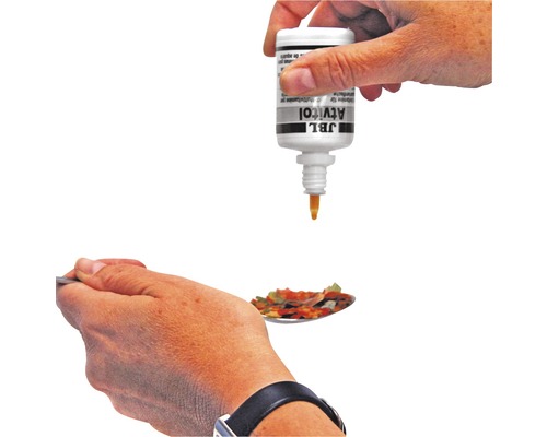 JBL Atvitol est versé goutte à goutte sur une cuillère de nourriture pour poissons.