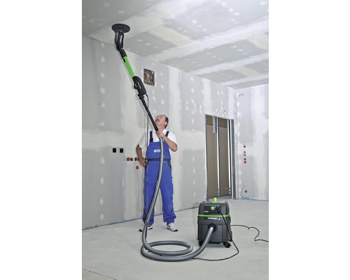 Un homme utilise une ponceuse à plafond avec aspirateur dans une pièce.