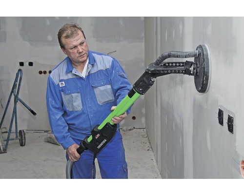 Un artisan ponce un mur avec une ponceuse à long manche Eibenstock