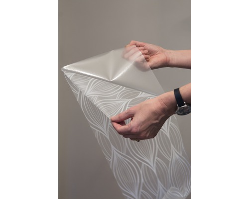 Eine Rolle Tapete mit Muster wird von zwei Händen gehalten.