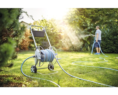 Scène de jardin avec dévidoir et personne arrosant la pelouse