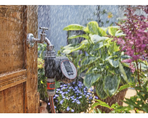 Minuteur d''arrosage sur robinet avec pluie dans le jardin