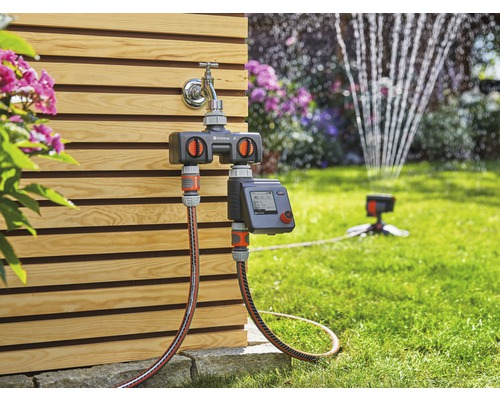 Distributeur d''eau Gardena Automatic sur robinet avec tuyau d''arrosage et arroseur de pelouse dans le jardin