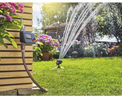 Système d''arrosage de jardin avec unité de commande, tuyau et arroseur de pelouse en fonctionnement