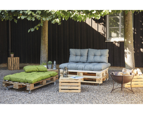 Aménagement de terrasse avec mobilier de palettes, coussins d''assise, caisse en bois et brasero
