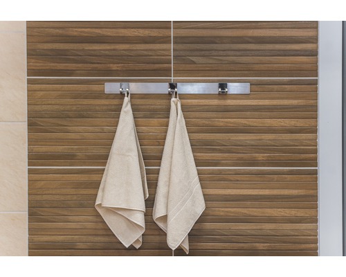 Vue de salle de bains avec serviettes sur un porte-serviettes devant un mur avec des carreaux de bois