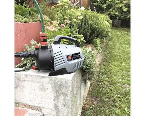 Pompe de jardin avec tuyau sur un socle en béton dans le jardin