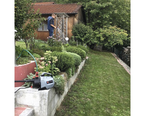 Arrosage de jardin avec pompe de jardin devant une maison