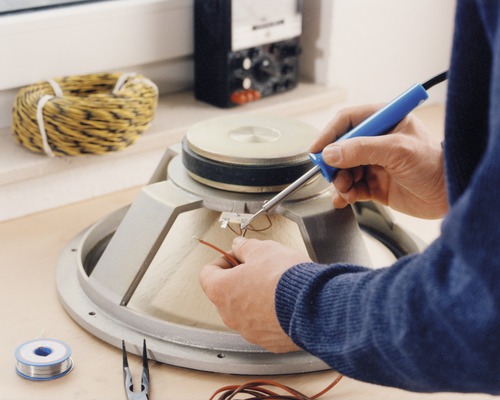 Löten eines Lautsprechers mit einem Lötkolben, inklusive Lötdraht, Zange und Kabel