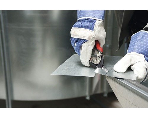 Une personne coupe une tôle avec des cisailles à tôle.