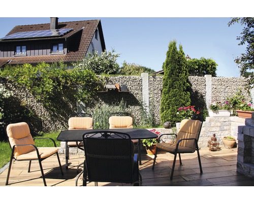 Terrasse mit Gartentisch und Stühlen vor Gabionenwand