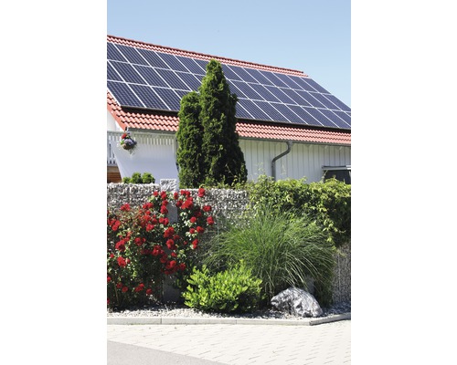 Haus mit Solaranlage auf dem Dach und Gabionenzaun im Garten