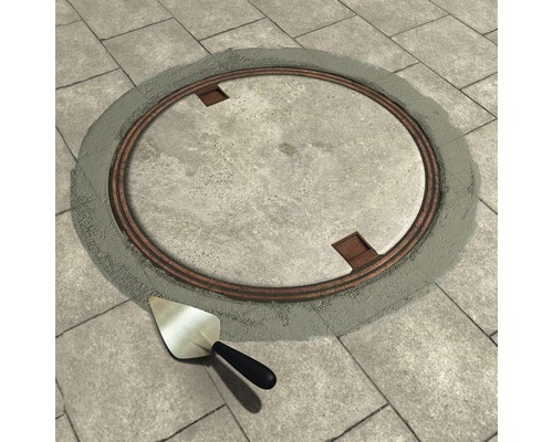 Couvercle de regard circulaire en métal avec truelle sur pavés