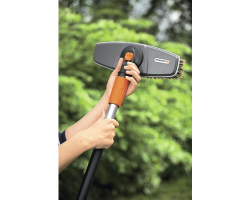 Person hält eine Waschbürste mit Teleskopstiel von Gardena.