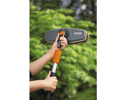 Person montiert eine Gardena Waschbürste an einem Teleskopstiel für Reinigungsarbeiten im Garten.