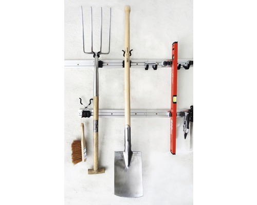 Outils de jardin tels qu''une fourche à fumier, une bêche et un niveau à bulle sur un rail mural