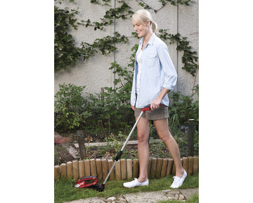 Une femme utilise un coupe-bordure dans le jardin.