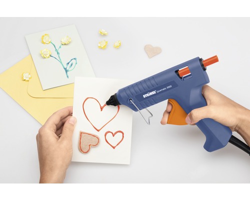 Personne utilisant un pistolet à colle chaude pour faire des cartes