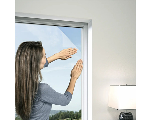 Frau bringt Fensterfolie an