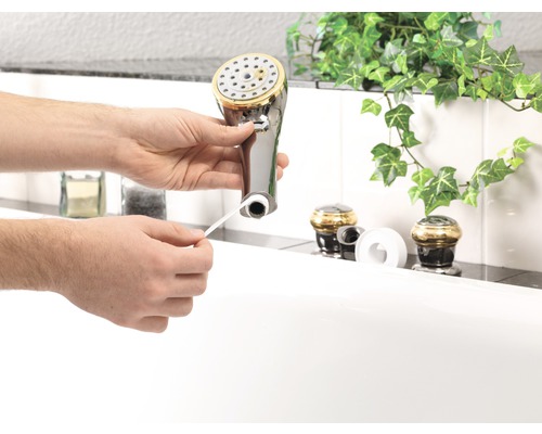 Un homme fixe du ruban d''étanchéité sur un pommeau de douche.