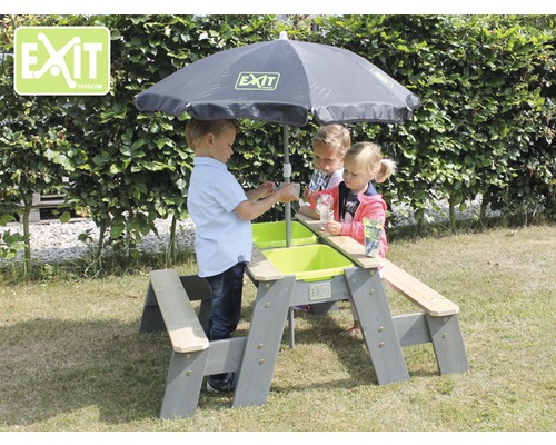 Kinder spielen an einem Picknicktisch mit Sandkasten und Sonnenschirm im Garten.