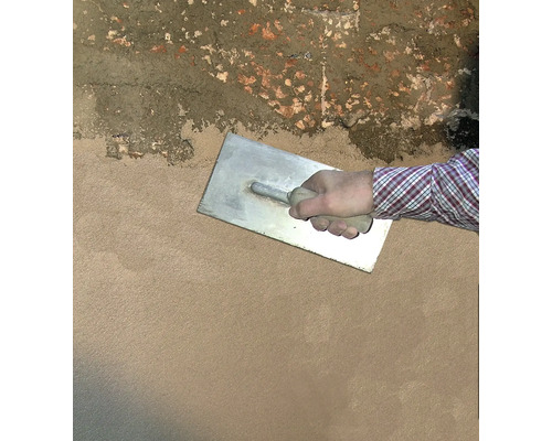 Artisan lissant l''enduit avec une taloche sur un mur