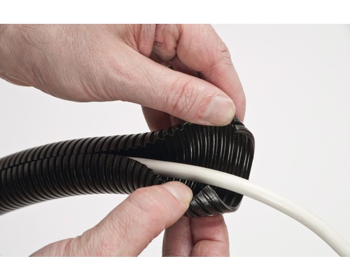 Une personne insère un câble blanc dans une gaine annelée noire