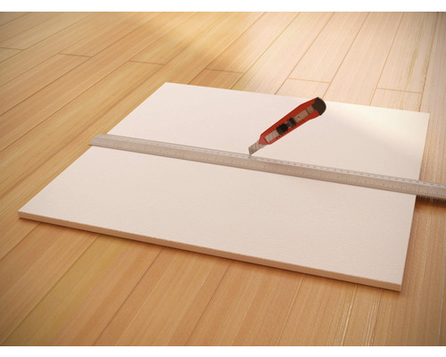 Panneau en mousse rigide avec règle et cutter sur parquet