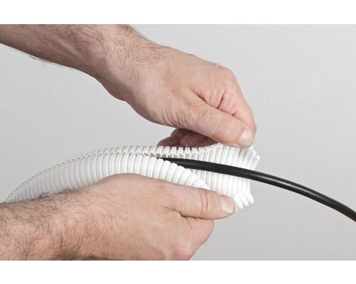 Eine Person legt ein schwarzes Kabel in ein weisses, geschlitztes Schutzrohr.