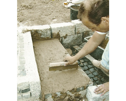 Un artisan joint des pierres avec une taloche à joints à l''extérieur.