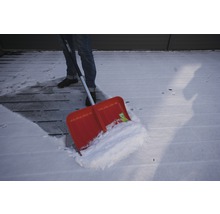 Personne déneigeant une terrasse en bois avec une pelle à neige
