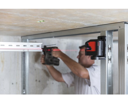 Un homme travaille avec un laser linéaire sur une structure métallique pour construction sèche.