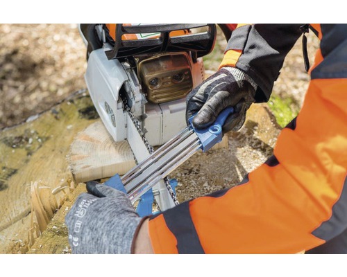 Une personne affûte une tronçonneuse avec un affûteur.