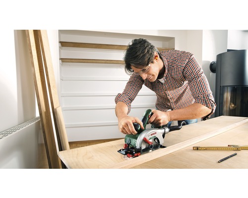 Homme coupant une planche en bois avec une scie circulaire portative, Logo Bosch